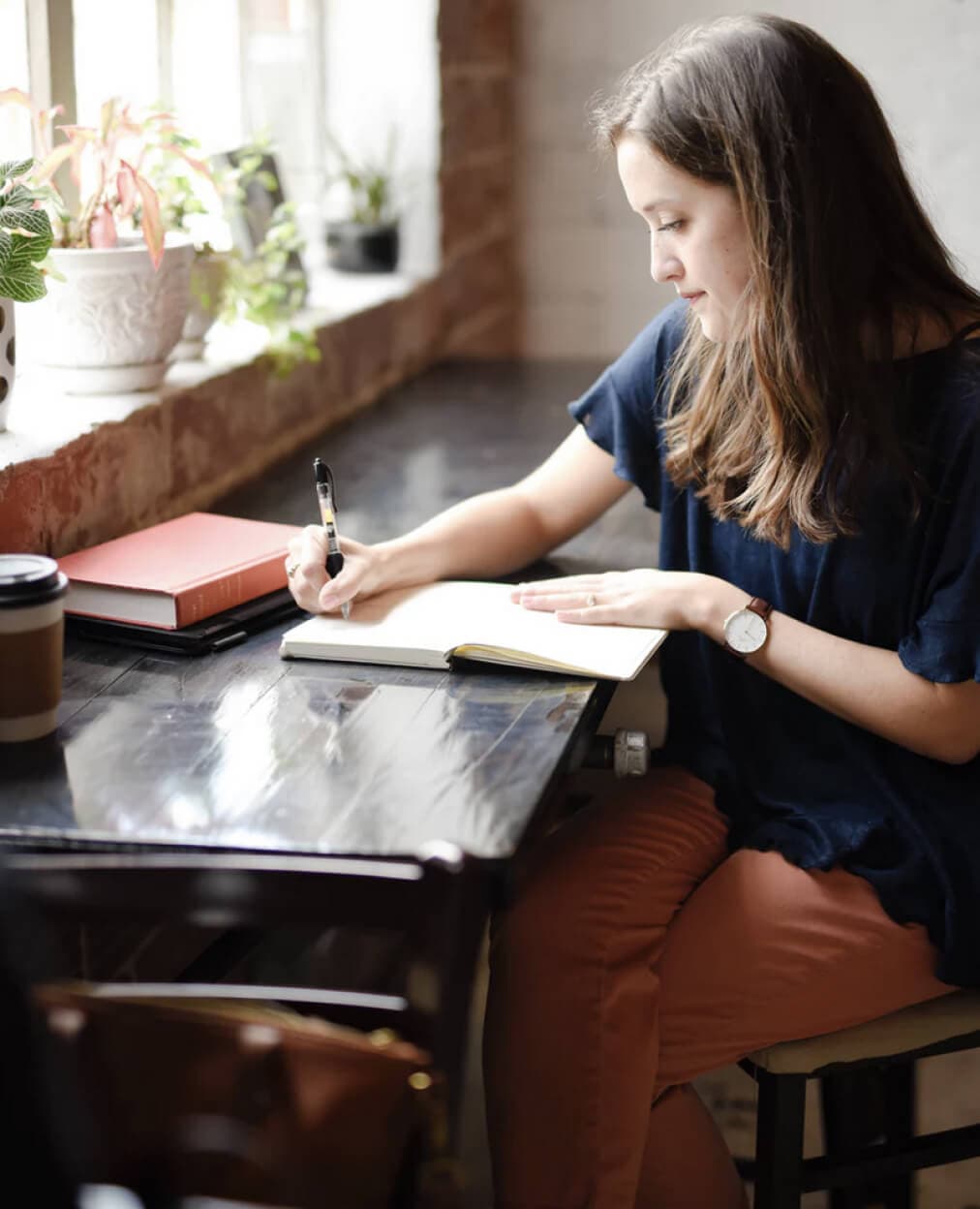 A person sitting by a window with a journal, writing thoughtfully